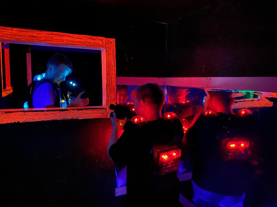 Zwei Laser-Game-Spieler, die sich durch ein Fenster in der Wand gegenseitig mit ihren Laserpistolen anvisieren.